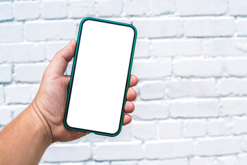 Close-up White mockup of a green smartphone in the hand of a man. Against the background of a light brick wall.
