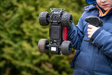 Boy holds remote control car by hand while wheels are spinning