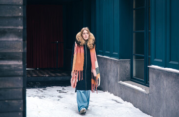 Stylish young woman in a jacket and with a scarf on a walk in winter.