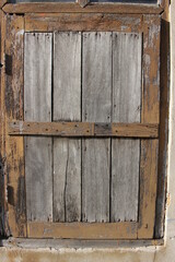 Old rustic closed brown wooden window shutter. Close-up view.