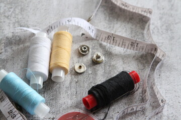 A set of seamstresses, threads, needles, buttons and a meter. Photo on a gray background. Ideal for a sewing workshop.