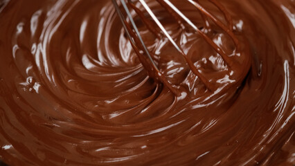 Stirring melted liquid chocolate with steel whisk. Mixing molten chocolate or dark caramel. Cooking chocolate dessert