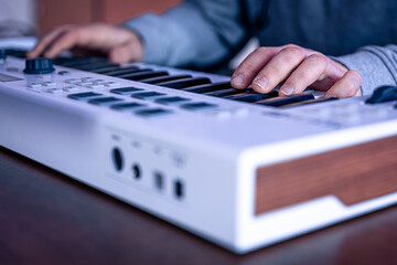Close-up, male hands are playing the midi keyboard.