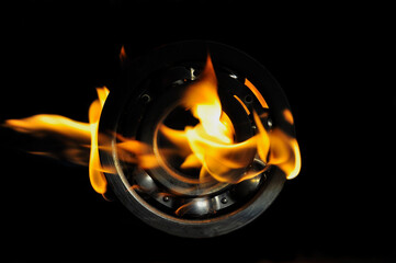 Metal ball bearing in a bright flame on a black background.