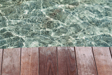 Wooden deck, tabletop on the surface of the water against the background of the pool.