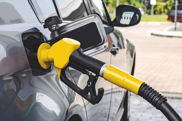 The gas station gun is inserted into the gas tank for refueling. Close-up view.