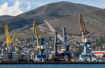 Fototapeta na wymiar The work of a portal crane in the bay of the city of Novorossiysk on a clear day in summer
