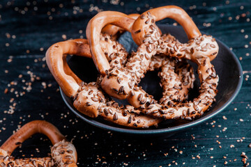 Fresh prepared homemade soft pretzels. Different types of baked bagels with seeds on a black background.