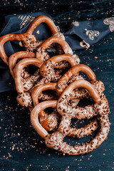 Fresh prepared homemade soft pretzels. Different types of baked bagels with seeds on a black background.