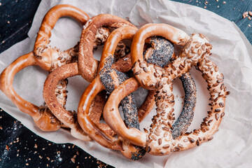Fresh prepared homemade soft pretzels. Different types of baked bagels with seeds on a black background.
