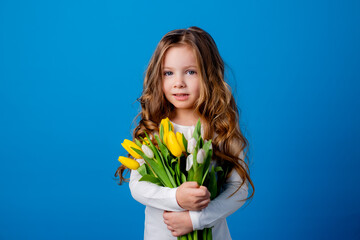 portrait of a charming smiling little girl with a bouquet of tulips in her hands. lifestyle. fresh flowers. International Women's Day. space for text. High quality photo