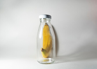 A ripe yellow banana in the peel is put in a glass bottle. Blank mock up. Healthy food to take with you