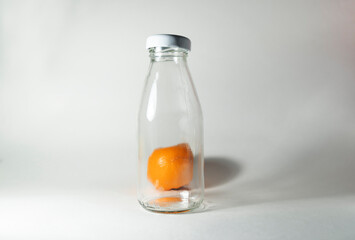 A whole orange lies in a transparent bottle with a white lid. Blank mock up. Healthy food to take with you