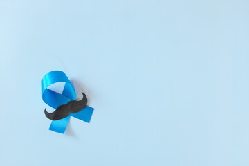 Top view of male hands holding light blue ribbon with mustache. Father's day, Men's Health and...