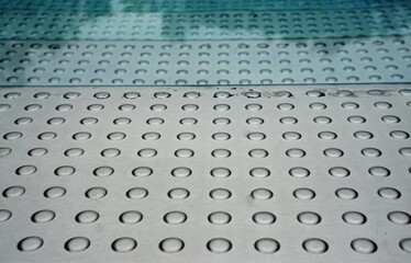 Treppenstufen aus Metall im Schwimmbecken mit Wasser und Spiegelung