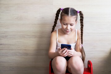 girl child with pigtails talking on the phone, getting homework on a cellular connection, during isolation and a pandemic, a convenient means of communication