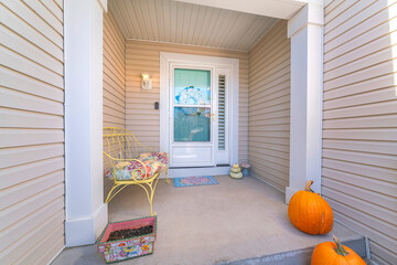 House exterior with beige vinyl lap siding and glass storm door over the wreath on the front door