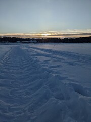 sunsen over the snow field with truck trails