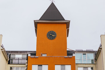 Clock on a high orange tower in orange color in Europe close-up
