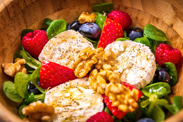 strawberries, berries and cheese colorful salad in a wooden cup on a wooden table