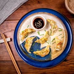 dumplings o a white and blue dish with soya sauce