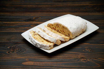 Sliced Traditional Christmas stollen cake with marzipan and dried fruit on wooden background