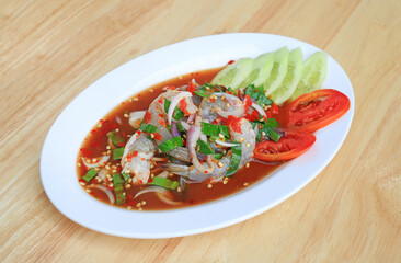 Shrimp spicy salad in dish on wood table background.