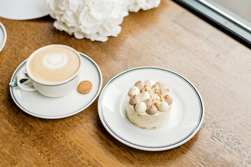 delicious dessert and a cup of coffee on the table. Enjoy a freshly baked dessert in a coffee shop, restaurant. A closeup shot of a little sweet decorative cake and a cappuccino. Soft selective focus.