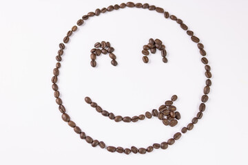 Cheerful emoticon made from coffee beans on a white background