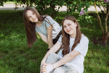 Two young happy teen girls having fun in the park on a summer day. Female friendship. Soft selective focus.