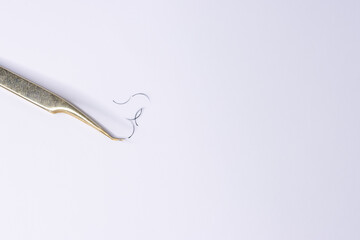 On a white background lies tweezers for eyelash extensions, eyelashes