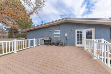 Deck of a gray house with a wood planks flooring and white railings