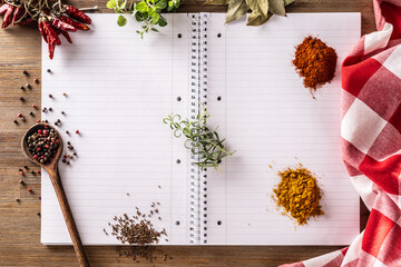 Open notebook with spices and herbs: chili, oregano, curry, basil, cummin ,bay leaf, and rosemary