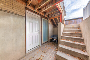 Basement white front door with scattered dry leaves on a concrete stairs