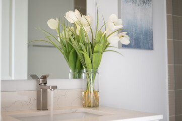 White flowers on the bathroom sink with the water running 
