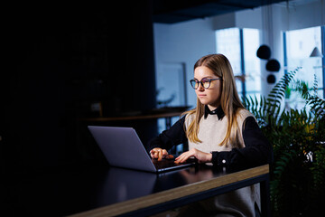 Beautiful smart attractive elegant woman businesswoman in a large company holds an online meeting with international business partners, she sits at a table at the workplace with a laptop