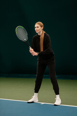 Beautiful lady and athlete with a racket in black sports dress on the tennis court. Fashion and sport concept.