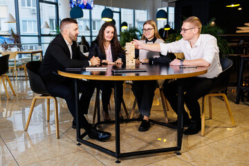 A company of colleagues in the office during a break plays the board game jenga. Fun board games for friends