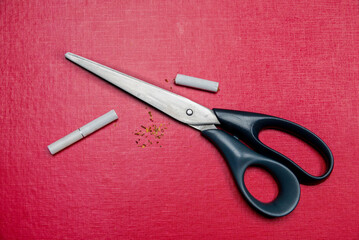 Cigarette in scissors on red background. Bad habit. Quit smoking as a New Year's resolution. High...