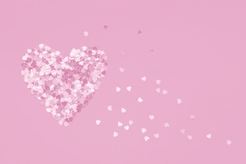 Pink Valentine's Day heart shape made of confetti on pink background. Monochrome style