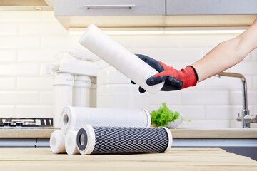 Hands holding a filter cartridge of domestic drink water treatment systems at kitchen background....