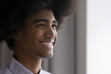 Happy African teenage guy with retro Afro hairstyle looking away, thinking, smiling at good...