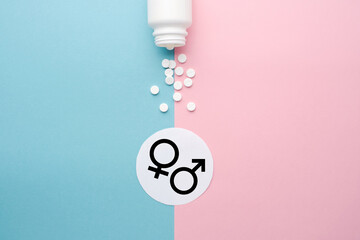 Pills scattered from a jar on a blue and pink background. Symbol of male and female. The concept of reproductive health and hormone therapy. Top view, background, space for text, copy space