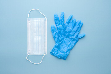 Medical disposable masks and gloves on blue background. The concept of the consequences of the covid-19 pandemic and pollution of nature with plastic