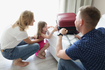 A couple with a little girl in a hotel close a suitcase, close-up