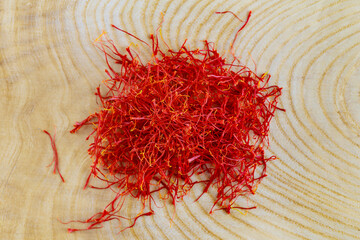 Heap of red stamens on a wooden background. The stamens are dried to obtain a ready-made spice.