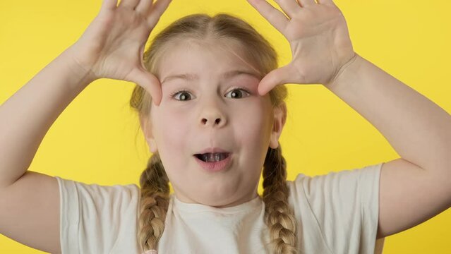 Little toothless girl having fun at yellow background. Cute child with lost milk tooth. Close-up in 4K, UHD