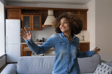 Happy cheerful Active teen Black girl woman dancing in home interior, enjoying fitness activity, music, tunes, singing song, having fun. Positive smiling teenage dancer training at home