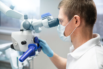 Dentist makes an operation using a dental microscope