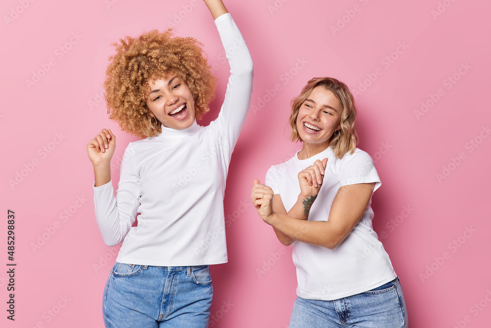 Canvas Prints People fun entertainment concept. Positive carefree women dance and sing together shake arms dressed in casual clothes move against pink background. Two glad girls move to music like nobody watching